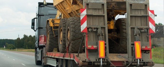 Heavy Truck being relocated on a trailer on the highway
